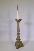 A gilt brass church torchere/pricket candlestick, decorated in relief with demons and angels,