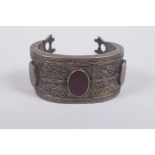 A Persian white metal bangle set with red agate cabochons, 7 x 5cm