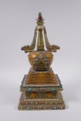 A Tibetan bronze stupa with gilt and silvered highlights and set with semi precious stones, 33cm