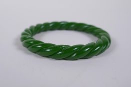 A Chinese carved green hardstone 'twist' bangle, 8cm diameter