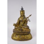 A Tibetan gilt bronzed metal figure of Buddha seated on a lotus throne, impressed double vajra
