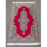 A full pile fine hand woven Iranian rug, signed and dated, with age, red ground with blue borders