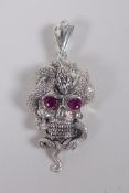 A white metal pendant in the form of a skull entwined with a snake, 5cm drop