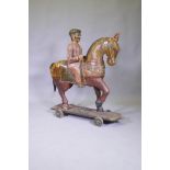 A carved and painted Indian figure of a mounted horseman, mounted on a base with wheels, 110cm high,