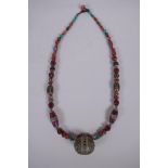 A Tibetan white metal, agate, coral and glass bead necklace with enamelled white metal feature bead,