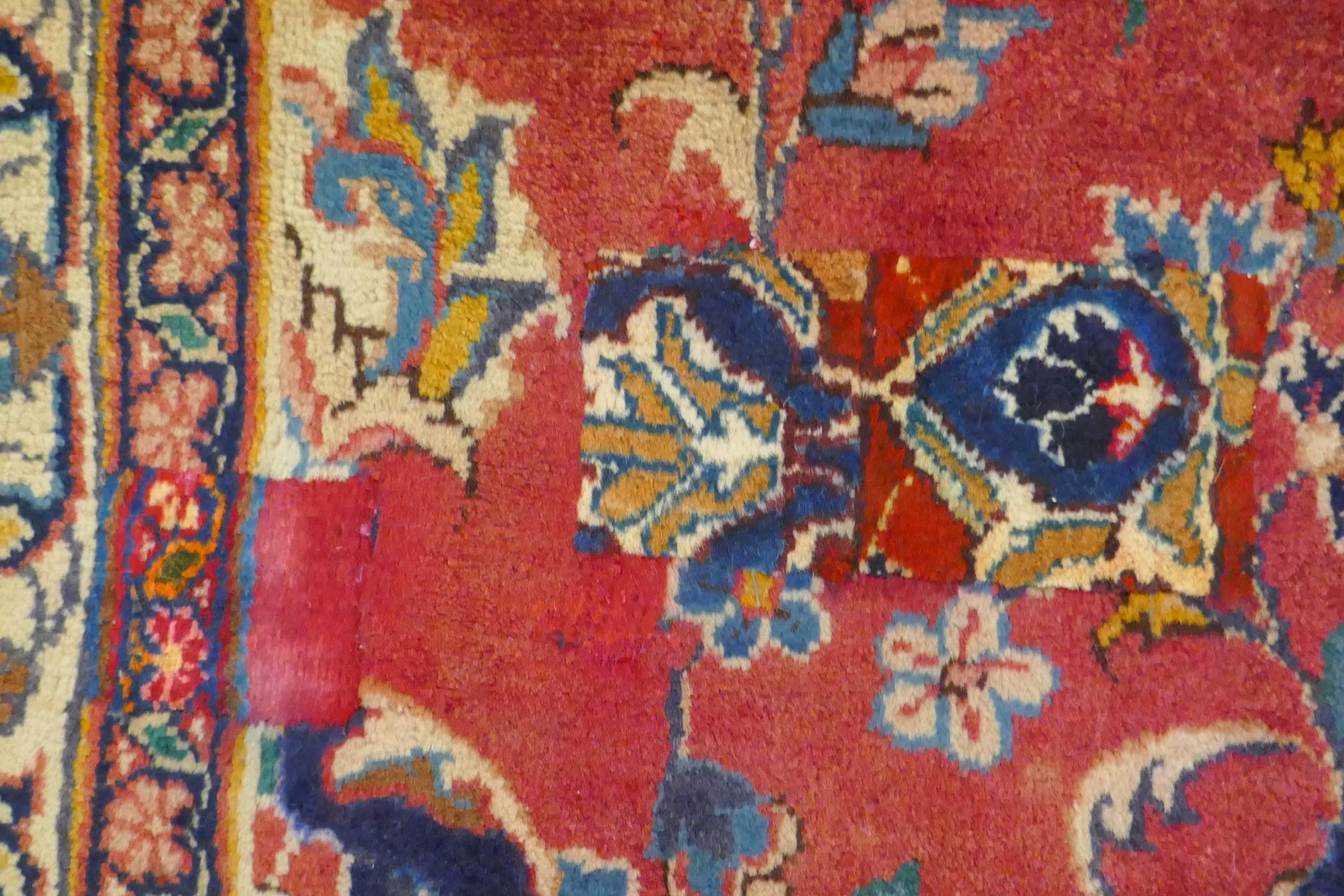 A washed red ground Persian Mashad carpet with traditional floral medallion design, signed by the - Image 6 of 8