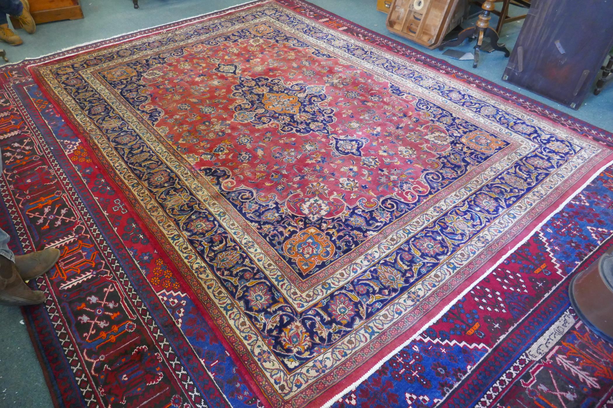 A washed red ground Persian Mashad carpet with traditional floral medallion design, signed by the - Image 2 of 8