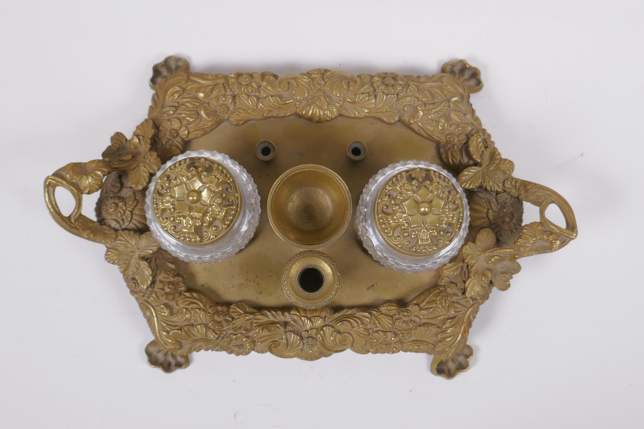 An antique brass desk stand with raised vine decoration and two glass inkwells, 30 x 20cm - Image 2 of 3