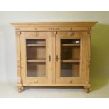 A C19th continental pine bookcase with two glazed door with applied fluted columns and lion mask