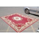 A large oriental red ground carpet with a cream floral medallion and borders, 240 x 330cm