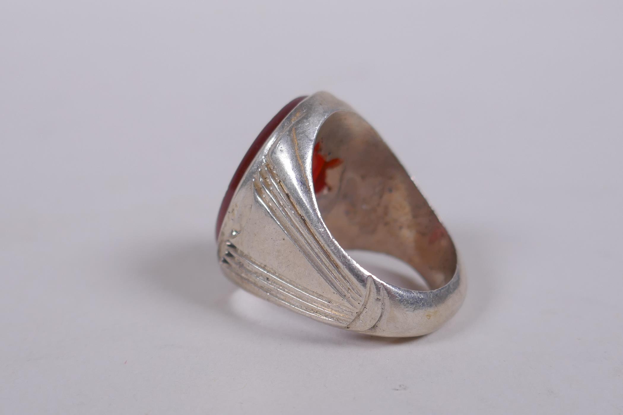 An Islamic white metal ring set with an agate intaglio seal, carved with Islamic script, marks to - Image 3 of 4