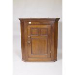 A Georgian oak hanging corner cupboard with three panelled door, original brass knob and escutcheon,