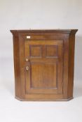 A Georgian oak hanging corner cupboard with three panelled door, original brass knob and escutcheon,