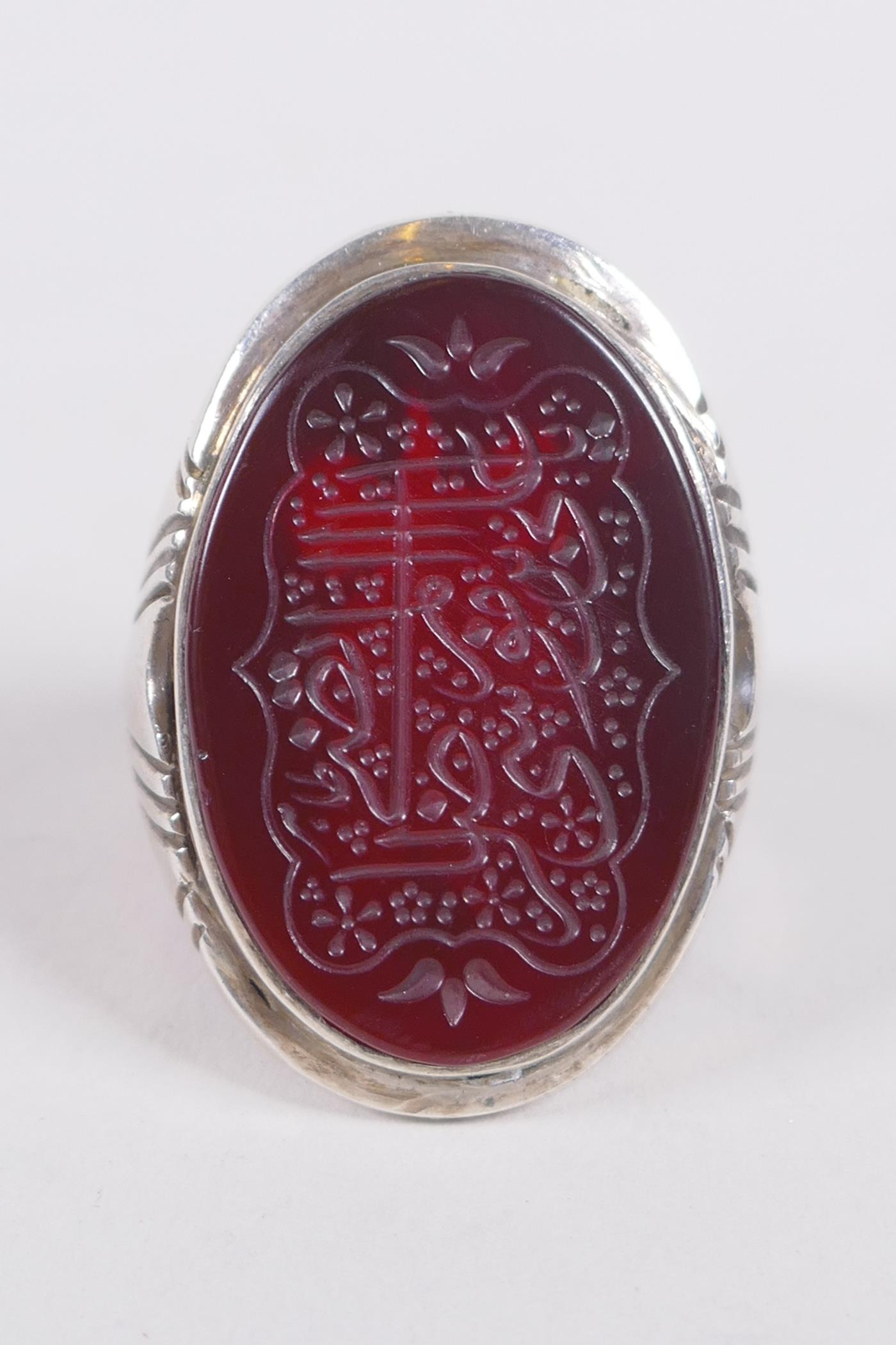 An Islamic white metal ring set with an agate intaglio seal carved with Islamic script, size W/X - Image 2 of 3