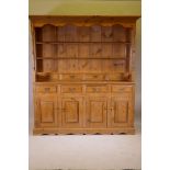 A pine dresser, the upper section with delft rack over four drawers, open sides, the base with