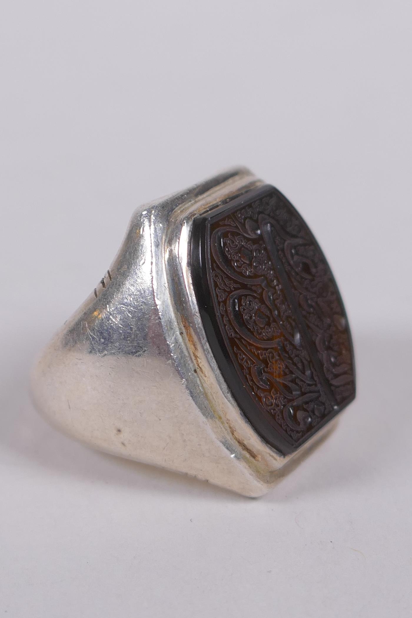 An Islamic white metal ring set with an intaglio seal carved with Islamic script, marks to interior,