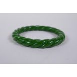A Chinese carved green hardstone 'twist' bangle, 8cm diameter