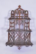 A mahogany Gothic style open fretwork hanging corner shelf, with pierced back and sides and three