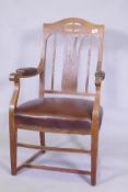 An Arts & Crafts oak armchair with pierced splat back, studded leather seat and arm rests, and