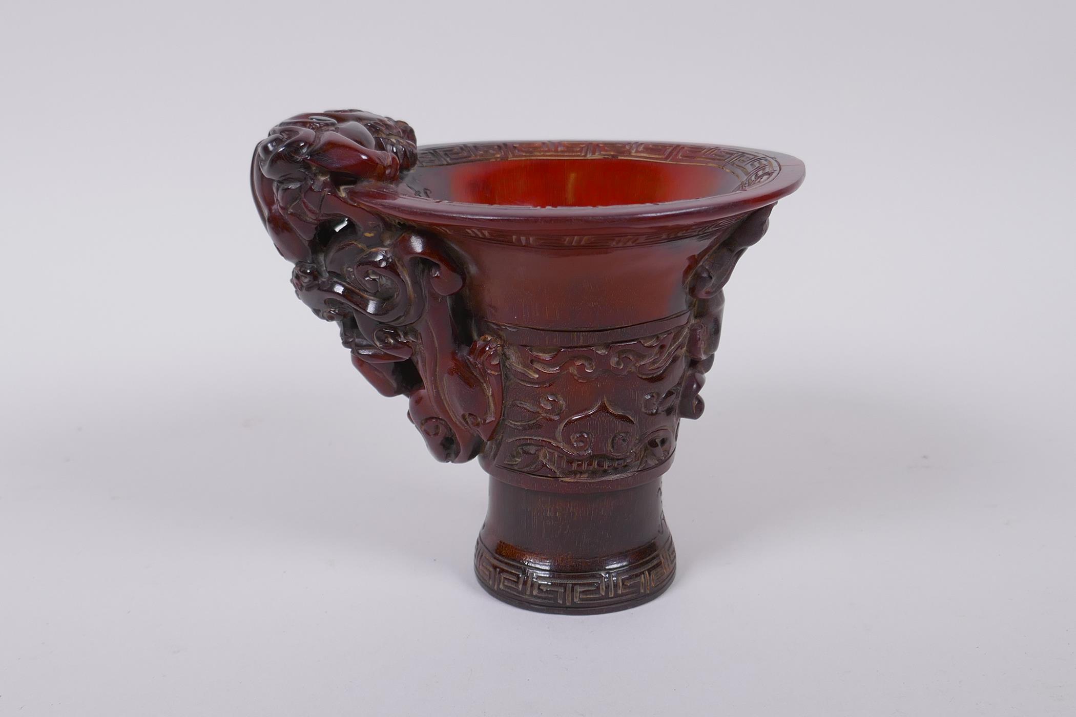 A Chinese horn libation cup with climbing kylin decoration, character mark to base, 12cm high