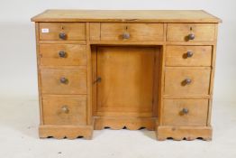 A C19th pine nine drawer kneehole desk with central cupboard raised on a shaped plinth base, 110 x