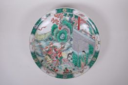 A Chinese KangXi style famille verte porcelain charger, decorated with warriors riding out from a