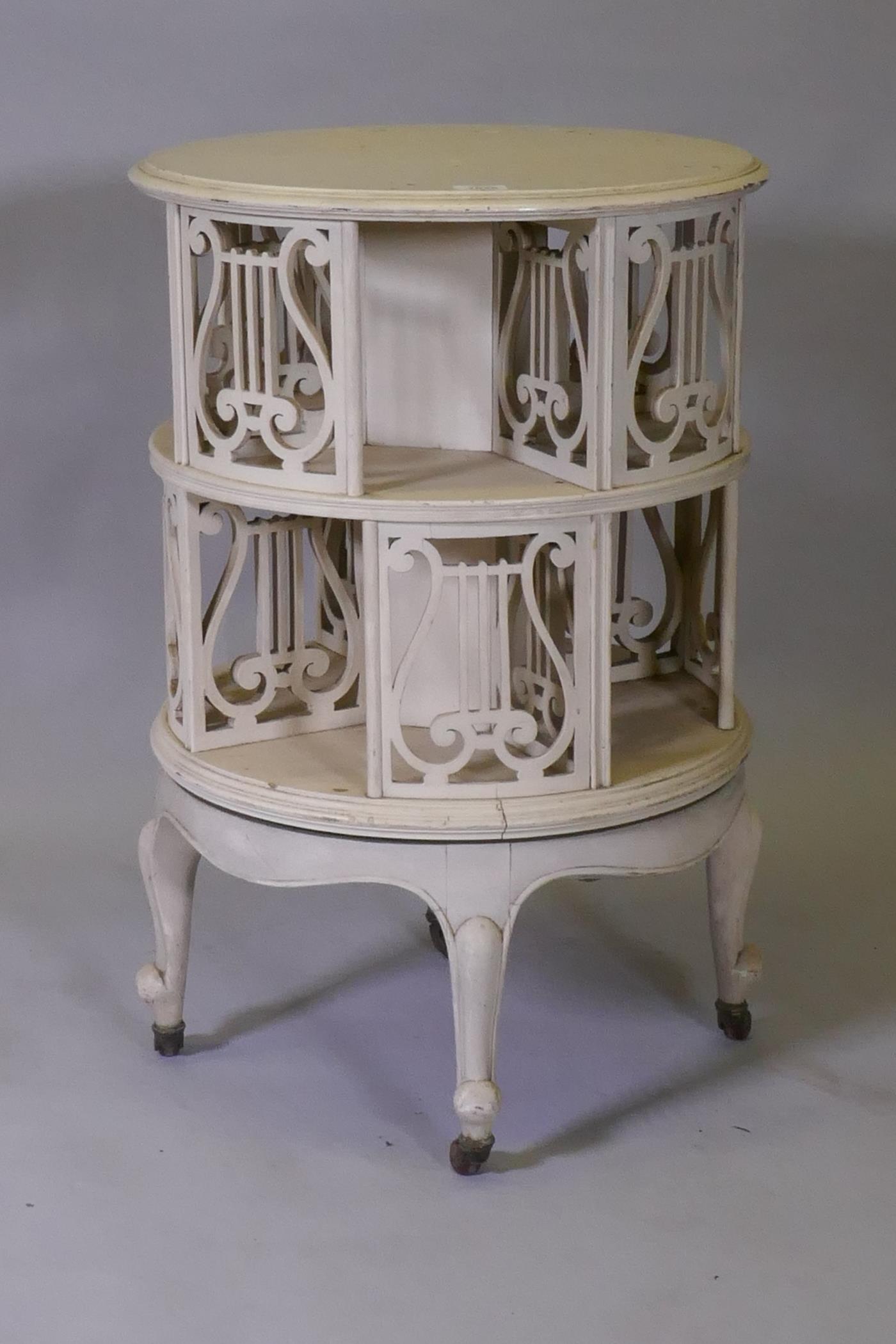 A Victorian revolving bookcase with pierced lyre shaped decoration, raised on cabriole supports with