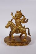 A Sino Tibetan gilt bronze figure of a deity riding a donkey, 22cm high
