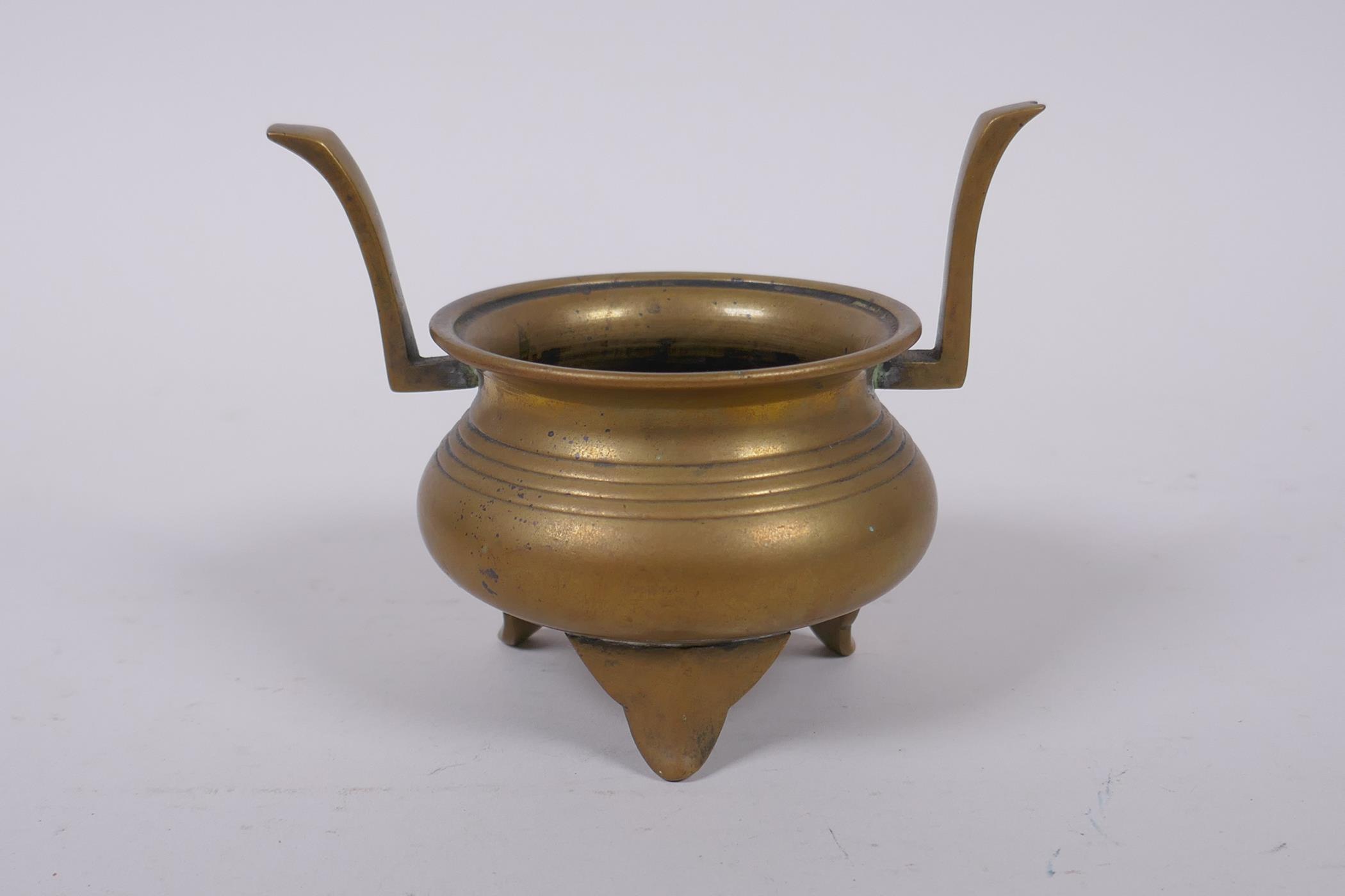 A Chinese bronze two handled censer on tripod supports, 9cm high