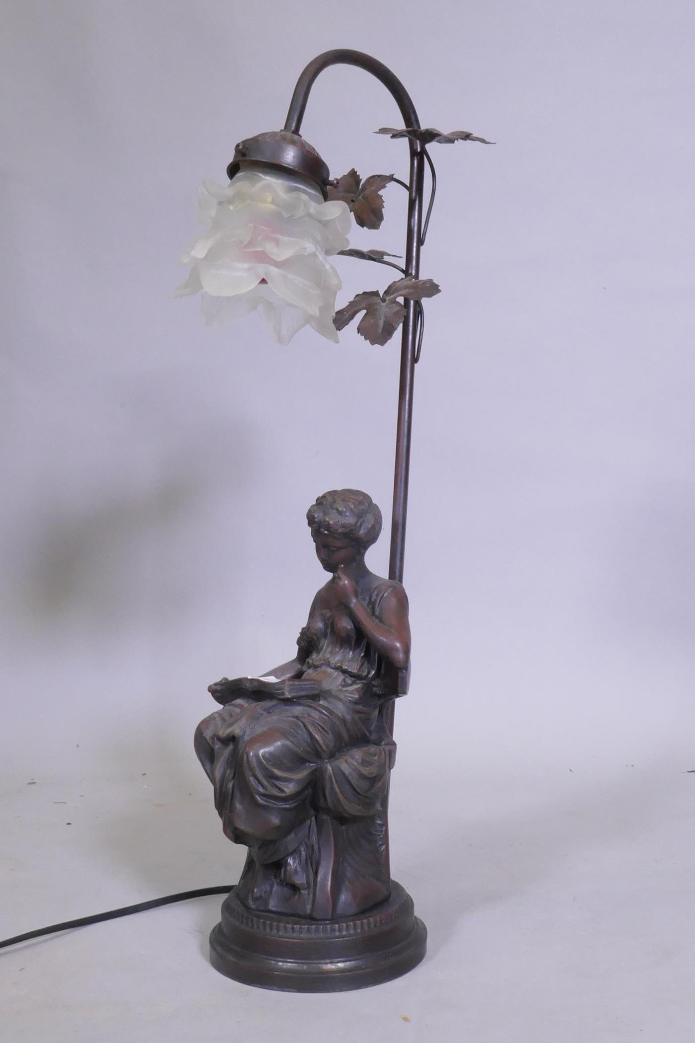 A bronzed composition table lamp in the form of a seated young woman reading a book, 57cm high