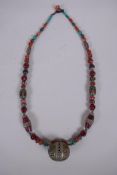 A Tibetan white metal, agate, coral and glass bead necklace with enamelled white metal feature bead,
