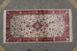 A Persian cream ground silk Tabriz rug with red borders, 62 x 122cm