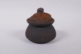 A Chinese part melted cast iron censer, opening to reveal part melted Buddha tokens, 12cm high