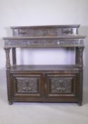 A Victorian oak buffet, the upper tier with two drawers, the lower with cupboards, with carved