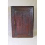 A Georgian oak hanging corner cupboard, fielded panel door and shaped shelves, 90 x 124cm