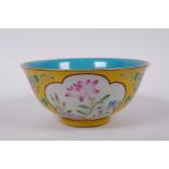 A polychrome porcelain rice bowl with famille rose enamel decorative panels within a yellow