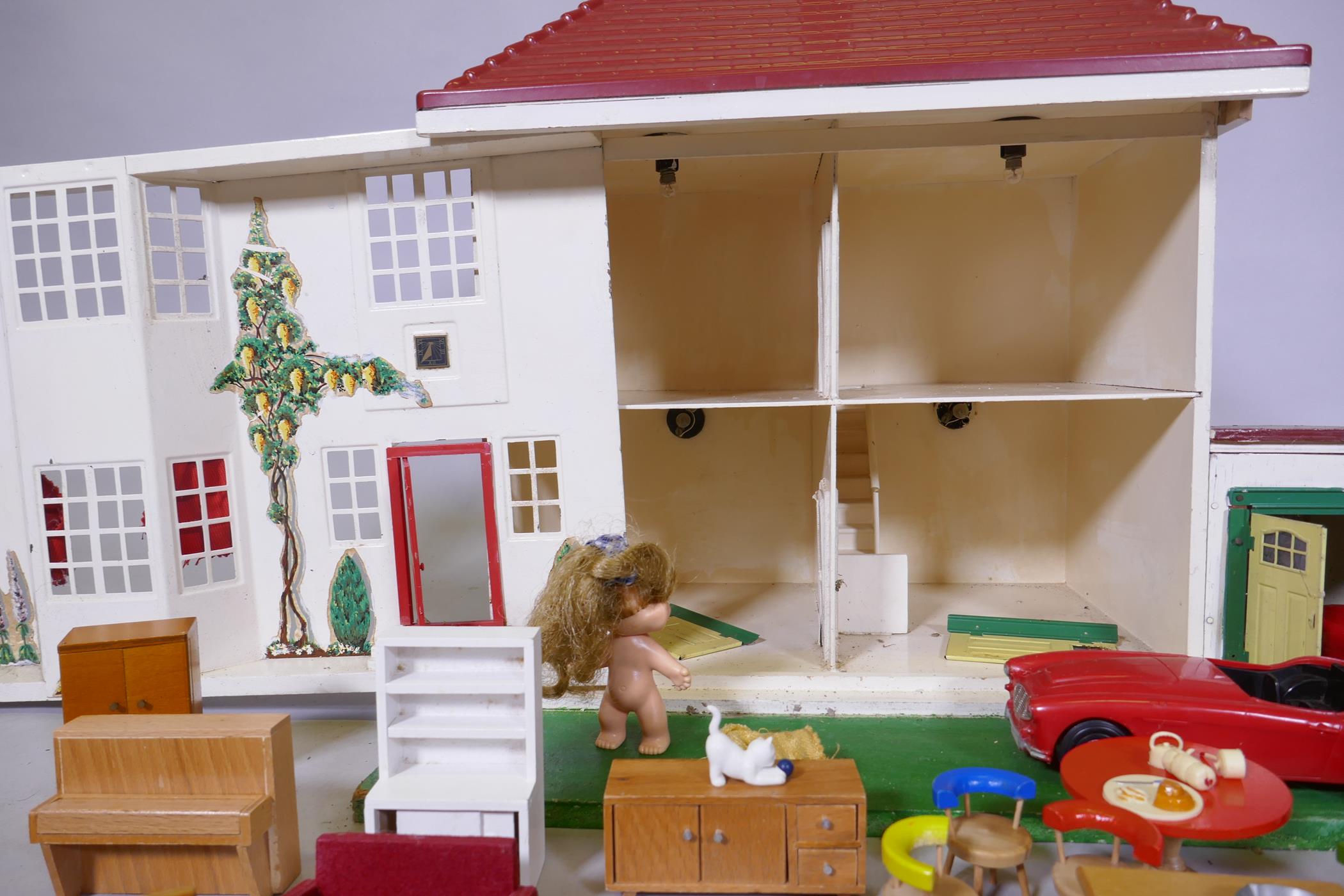 A mid century doll's house with sliding metal front, illuminated and with furnishings, mounted on - Image 7 of 7