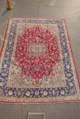 An Iranian red ground wool Isfahan carpet, with floral medallion design and blue borders, 275 x