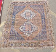 An antique Persian rust ground wool Hamadan rug with two cream ground geometric medallions, AF,