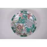 A Chinese KangXi style famille verte porcelain charger, decorated with warriors riding out from a