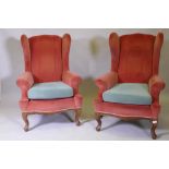 A pair of Georgian style wing back armchairs, with shaped backs