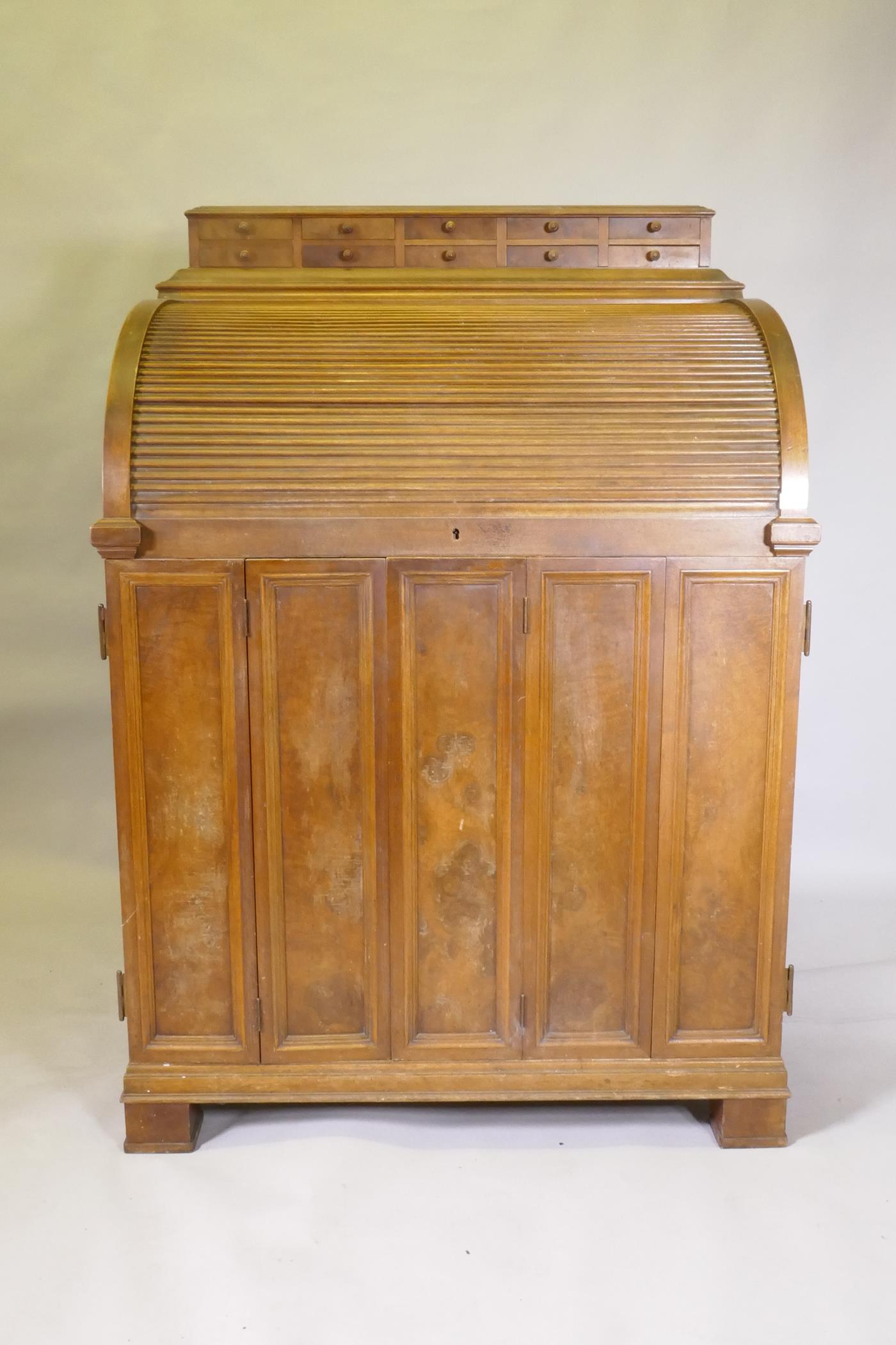 A late C19th/early C20th walnut tobacconist's shop cabinet, the roll top opening to reveal drawers