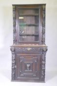 A C19th French carved oak bookcase with lion mask decoration and a glazed upper section, 84 x