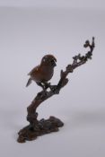 A Japanese style bronze okimono of a bird perched on a branch, 10cm high