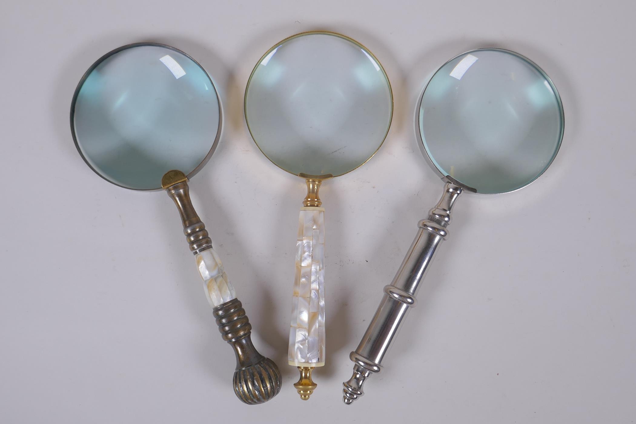 Two brass magnifying glasses with mother of pearl handles, and a similar chromed metal magnifying
