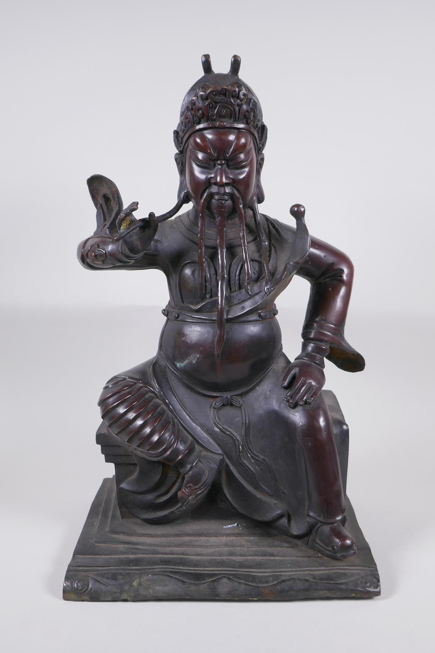 A large Chinese bronze figure of an immortal warrior seated on a throne, 45cm high