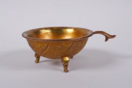 A Chinese gilt metal libation cup on tripod supports with kylin decoration, 9cm diameter