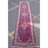 A Persian red ground wool runner with multi colour geometric medallion design, 85 x 340cm