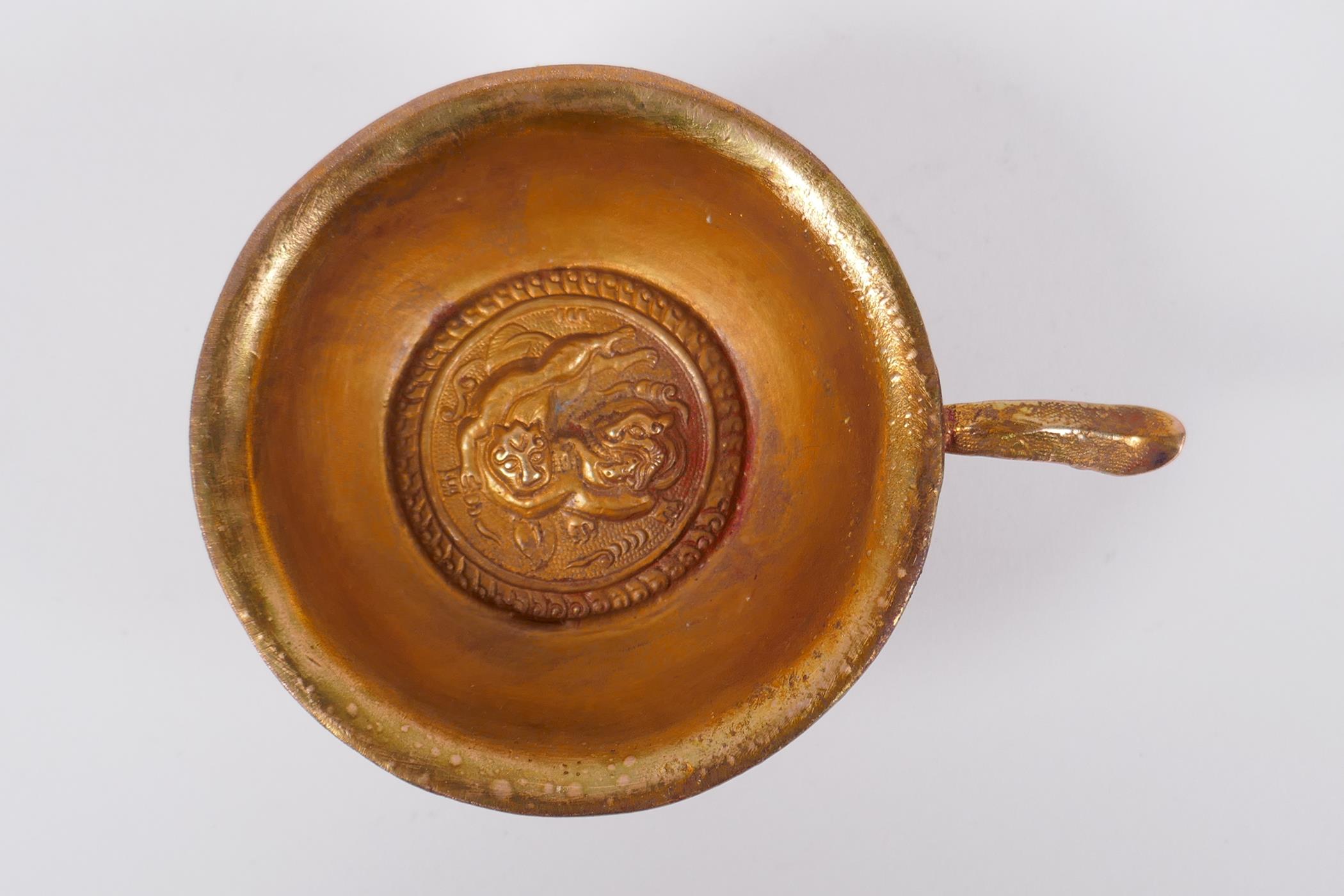 A Chinese gilt metal libation cup on tripod supports with kylin decoration, 9cm diameter - Image 2 of 3