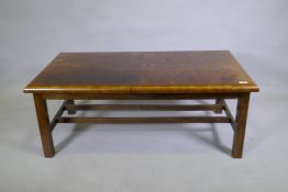 A burr walnut top coffee table with moulded edge, raised on square supports united by H